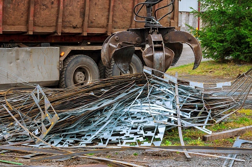 A grapple truck loads scrap industrial metal for recycling