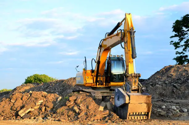 Excavator with crusher bucket for crushing concrete. Construction waste recycling for construction mix. Sifting and grinding bucket for the separation of concrete into fractions of higher quality.