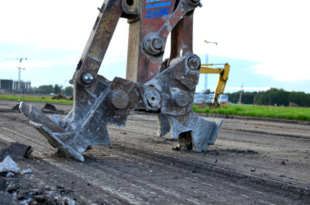 Excavator with hydraulic shears breaks asphalt on a construction site. Hydraulic shear crusher pulverizer for excavator. Heavy-duty mechanical concrete crusher. Attachments Equipment